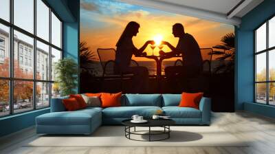 Female and man's silhouettes on sunset sit at table with two gla Wall mural