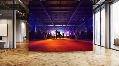 People stand, sit at table and look at illuminated stage Wall mural