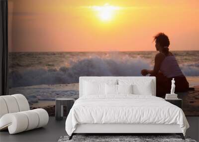 silhouette sitting young woman on sunset wavy beach Wall mural