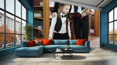 Three students, two girls and boy looking in book that holds eldest girl Wall mural