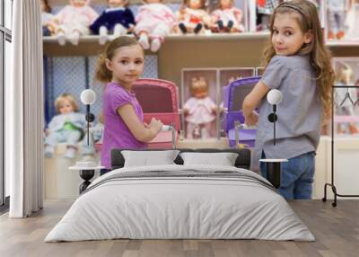 Two girls in toy store with rows of dolls  purchased buggy Wall mural