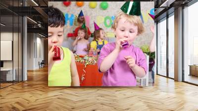 two little boys blow in multicolor party blowers at birthday Wall mural