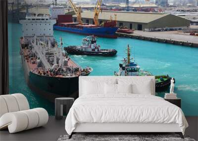 two small boats docked to industrial ship in port at sunny day Wall mural