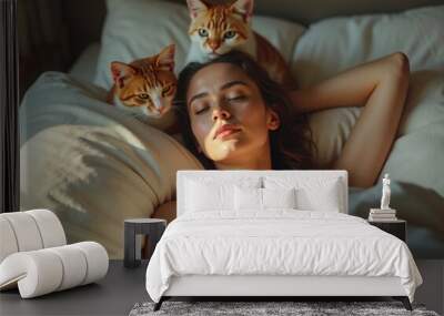 A woman peacefully sleeps in bed as two orange tabby cats cuddle around her in soft morning light Wall mural