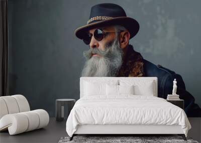 Photo of an old man with a long gray beard and sunglasses wearing a hat, standing fashionably dressed against a gray background, posted Wall mural