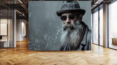 Photo of an old man with a long gray beard and sunglasses wearing a hat, standing fashionably dressed against a gray background, posted Wall mural