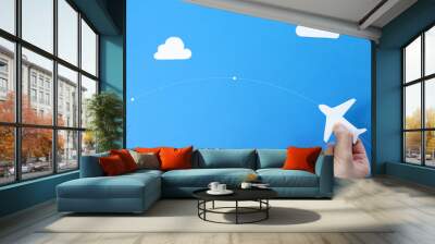 paper airplane in hands on a blue background Wall mural