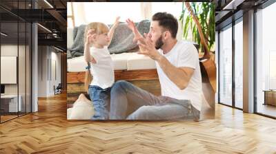 Father and daughter. Handsome young man and little cute girl scare each other like wild animals at home, have fun. Dad and child laugh. Father's day. Wall mural