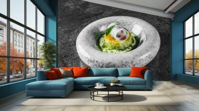 A vibrant gourmet dish featuring a colorful, spherical jelly adorned with fruit pieces, resting on a bed of finely diced green ingredients in a speckled white bowl Wall mural