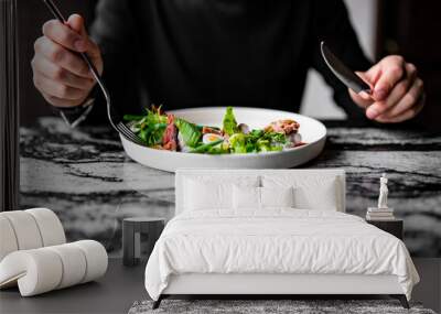 Hands of a man with a fork and knife eat Salad nicoise. Tuna, with green beans, tomatoes, potatoes and a vinaigrette mustard dressing in white plate Wall mural