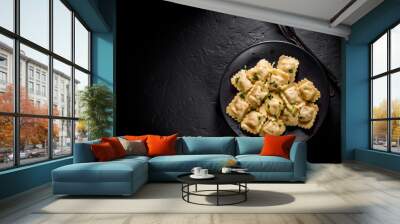 Meat dumplings - russian pelmeni, ravioli with meat in black plate on Dark grey black slate background Wall mural