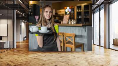 portrait young waitress standing in cafe. girl the waiter holds in bunches a tray with utensils. res Wall mural