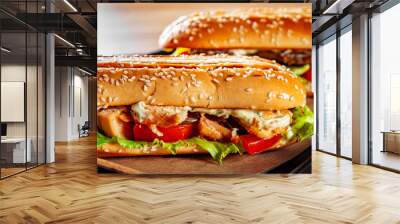 Two long submarine sandwiches with meat, cheese, bacon, tomatoes, lettuce, cucumbers and onions on wooden table background Wall mural