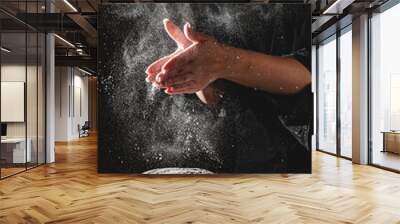 woman chef hand clap with splash of white flour and black background with copy space. woman's hands Making bread Wall mural