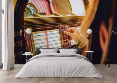 woman hand pushing buttons to play song on old Jukebox, selecting records Wall mural