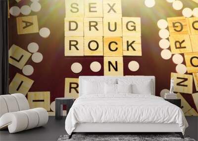 Wooden blocks on a pink background spelling words Sex Drug Rock n Roll surrounded by tablets. Art Style Wall mural