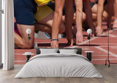 Group of male track athletes on starting blocks.Hands on the starting line.Athletes at the sprint start line in track and field Wall mural