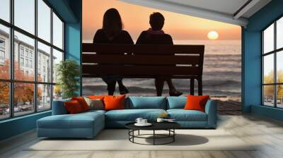 Silhouette of two women on a bench by the sea Wall mural