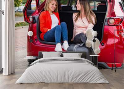 Two young girls rest from packing luggage in car Wall mural