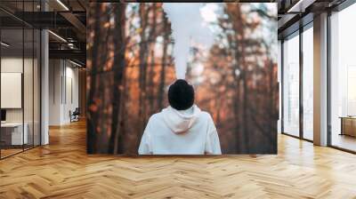 A young man in a white hoodie in an autumn park exhales a cloud of smoke Wall mural