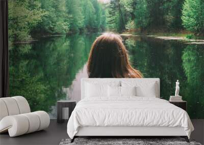 girl stands with his back to the camera. against the background of a beautiful river. green forest Wall mural