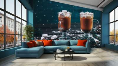 Two hot coffees with milk and marshmallows on the table with Christmas tree branches, fake snow and a caramel cane. Wooden blue background Wall mural