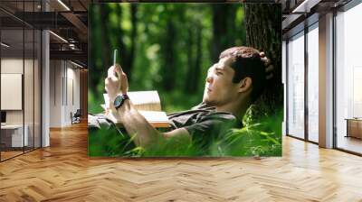 Young Caucasian man or student reading a book in the Park. Summer time and outdoor recreation Wall mural