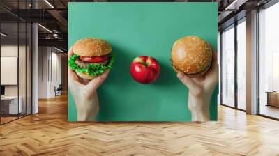 Unhealthy vs healthy food. Burger and apple in different hands on green background . Choice between fast foods and vegetables, Wall mural