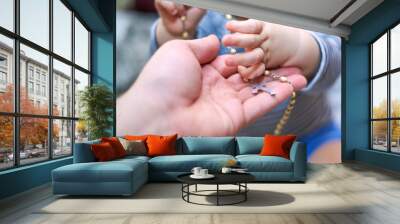 A child takes a rosary from his dad's hand Wall mural