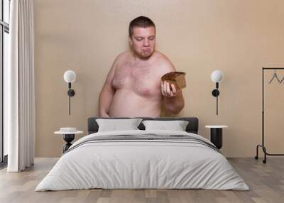 A man measures his fat belly with a meter and holds bread in one hand Wall mural