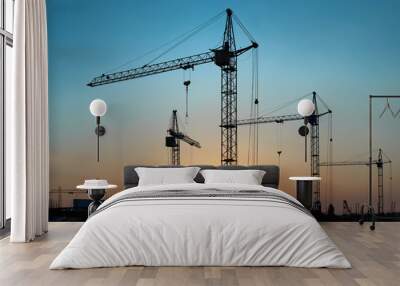 Industrial landscape with silhouettes of constraction cranes on dramatic sunset background Wall mural