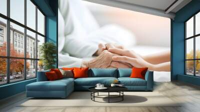 Two hands. A young woman holds the hand of an older woman. Caregiver at home. Concept of health care for senior elderly old people. Space for text white background. Generative ai. Wall mural