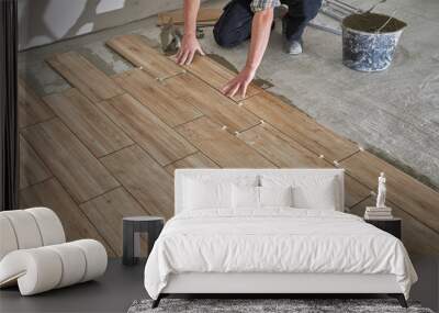 Hands of the tiler are laying the ceramic wood effect tiles on the floor Wall mural