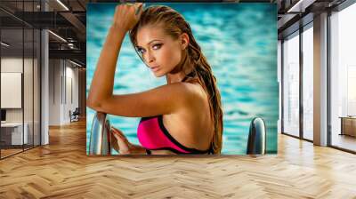 Beautiful sexy blonde woman with long hair and tanned body wearing swimsuit posing at the swimming pool. Wall mural