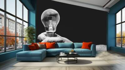 Black and white photo. Hand holding light bulb on black background. Wall mural