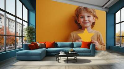 Cheerful boy holding yellow star against bright background Wall mural