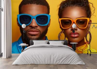 Stylish couple wearing vibrant sunglasses against bright yellow background, showcasing modern fashion and bold colors. Their confident expressions add to dynamic visual appeal Wall mural