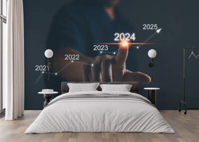 Business plan and vision for 2024. Startup for business. Performance goals for growth ,Businessman uses his finger to kick the 2024 graph showing marketing strategies for the annual business plan. Wall mural