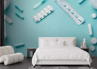 An assortment of medicine capsules, tablets, and containers on a teal background, ideal for health and wellness themes. Wall mural