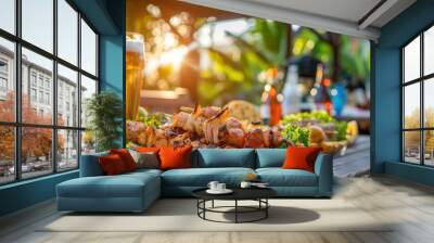 Outdoor BBQ party with grilled food, beer, and refreshing drinks on a rustic table at sunset, set against a lush garden background. Wall mural