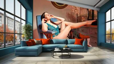 Beautiful and young woman lying on armchair vintage interior. Wall mural