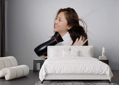 Asian women are using the hair dryer to dry. On a white background Wall mural