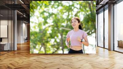 Beautiful young healthy Asian woman running in the park in the morning. Health care concept. Wall mural