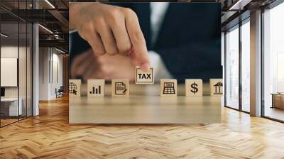 Businessman Hand holding Wooden blocks with the word tax and tax icons.Financial research, government taxes, Tax and Vat concept.Data analysis, financial research, and report.tax return.tax time. Wall mural