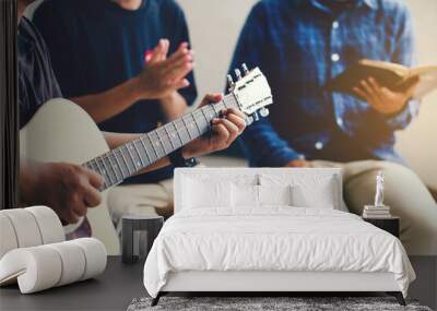 Christian family worship God in home with  playing guitar, and holding holy bible .Group christianity people reading bible together.Concept of wisdom, religion, reading, imagination. Wall mural