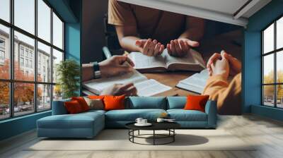 Christians and Bible study concept.Christian family sitting around a wooden table with open bible page and holding each other's hand praying together. Wall mural