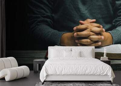 Hand of man while praying for the Christian religion, Man praying with his hands together with Bible on a wooden table. begging for forgiveness and believing in goodness. copy space for banner Wall mural