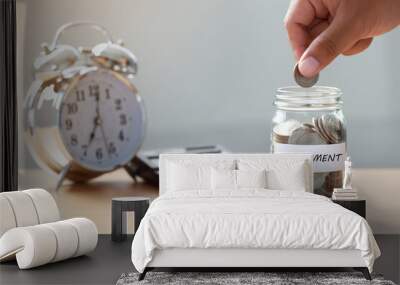 Hand putting Coins in glass jar with calculator and alarm clock for time to money saving for retirement concept ,  retirement planning. Wall mural