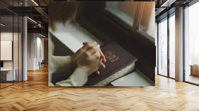 Young woman praying with hands together on the holy bible with light from the window. spiritual and religious prayer, talk to God. love and forgiveness. faith for god and teachings from the Bible. Wall mural