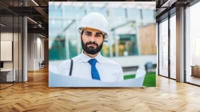 Young architect at work with helmet and plans for the project in hand Wall mural